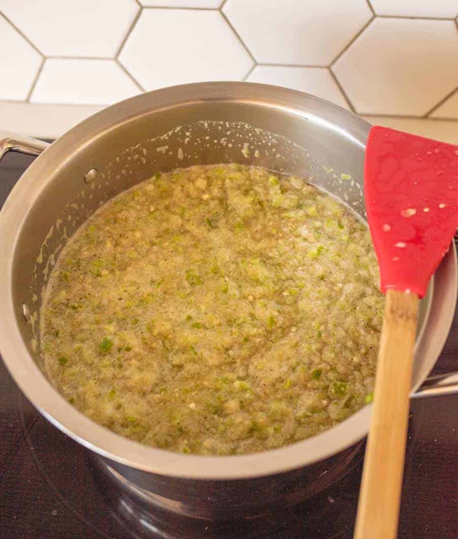 Green tomatillo salsa in a stock pot on cooktop.