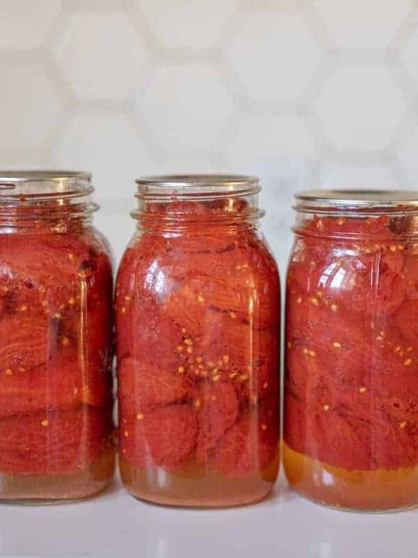 three finished jars of tomatoes sitting in a row