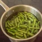 green beans in water in pot on cooktop