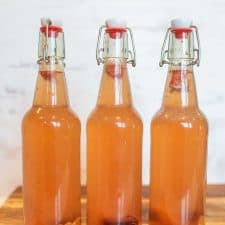 thee wire lid carafe bottles of orange second ferment kombucha with oranges and cherries in the bottom