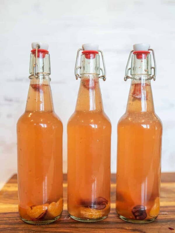 thee wire lid carafe bottles of orange second ferment kombucha with oranges and cherries in the bottom for how to make kombucha.
