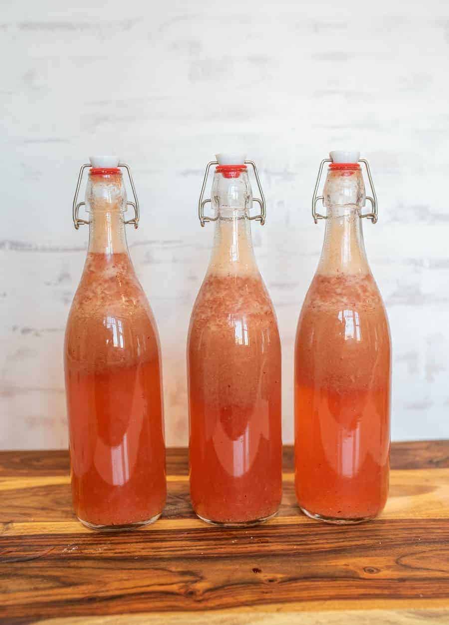 thee wire lid carafe bottles of pink -orange colored liquid.