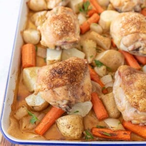 oven roasted chicken thighs, carrots, potatoes, and onions on enamel baking sheet with garnish