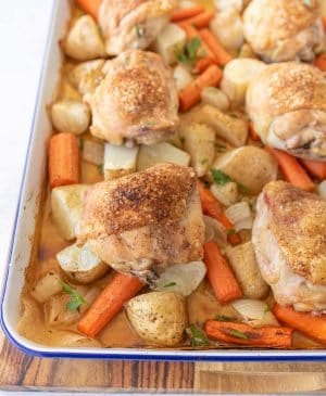 oven roasted chicken thighs, carrots, potatoes, and onions on enamel baking sheet with garnish