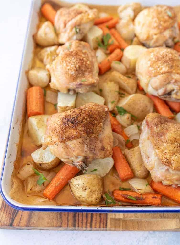 oven roasted chicken thighs, carrots, potatoes, and onions on enamel baking sheet with garnish