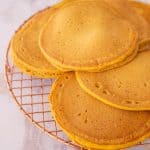 6 golden orange pancakes on a cooling rack
