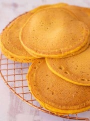 6 golden orange pancakes on a cooling rack