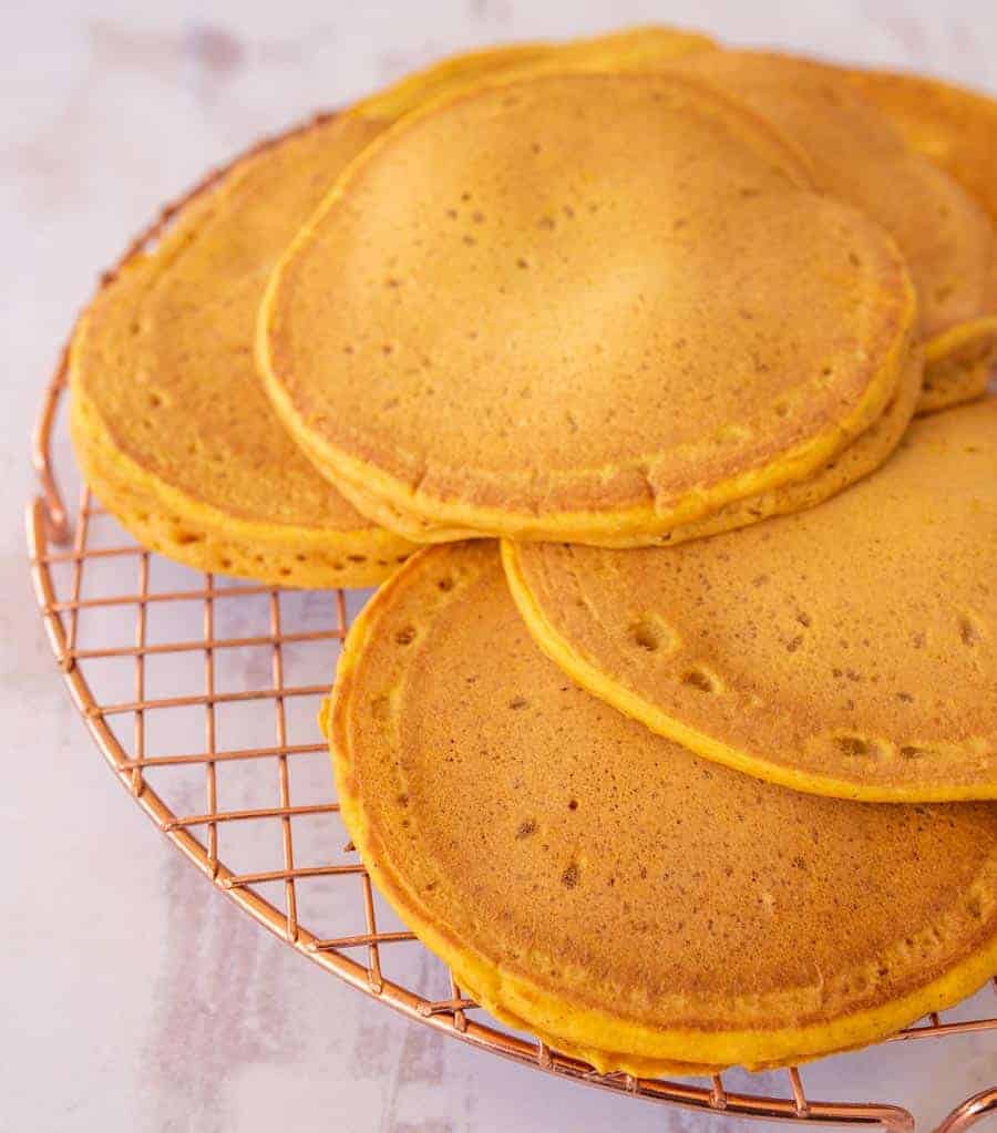 6 golden orange pancakes on a cooling rack