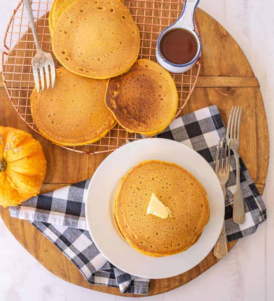 pancakes on cooling rack and some on a plate with butter