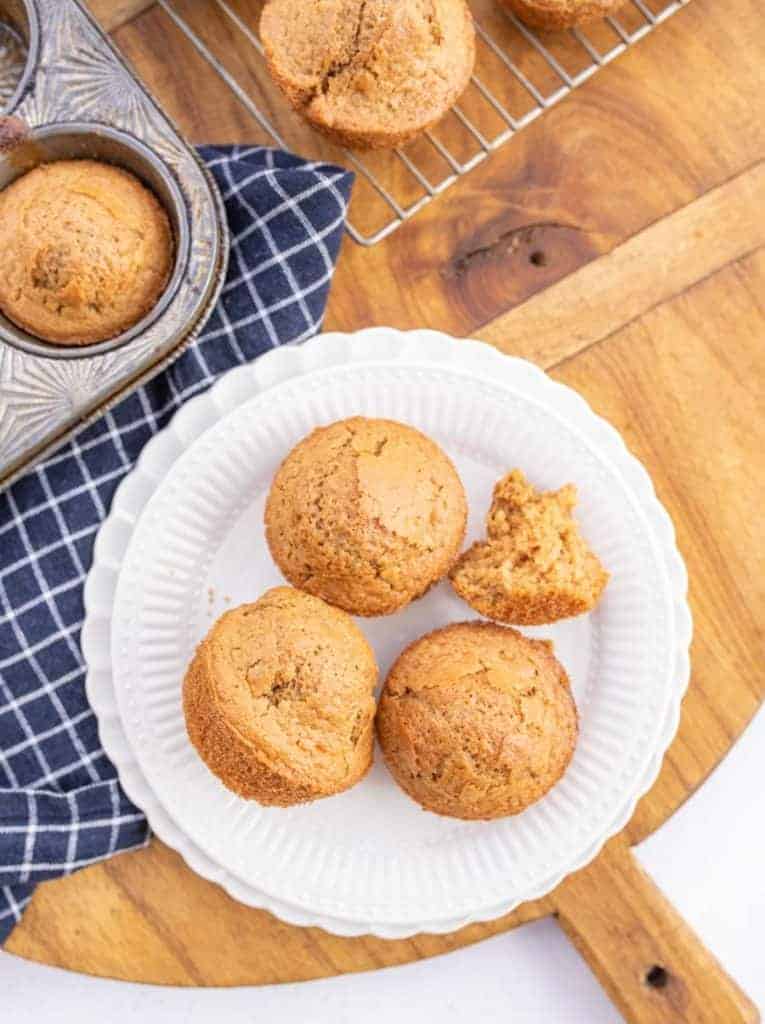 3 sourdough muffins on a white plate on a tan wood board