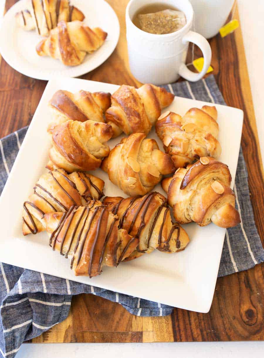 three kinds of croissants on a white plate with tea