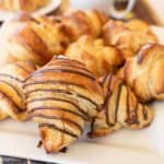 three kinds of croissants on a white plate with tea