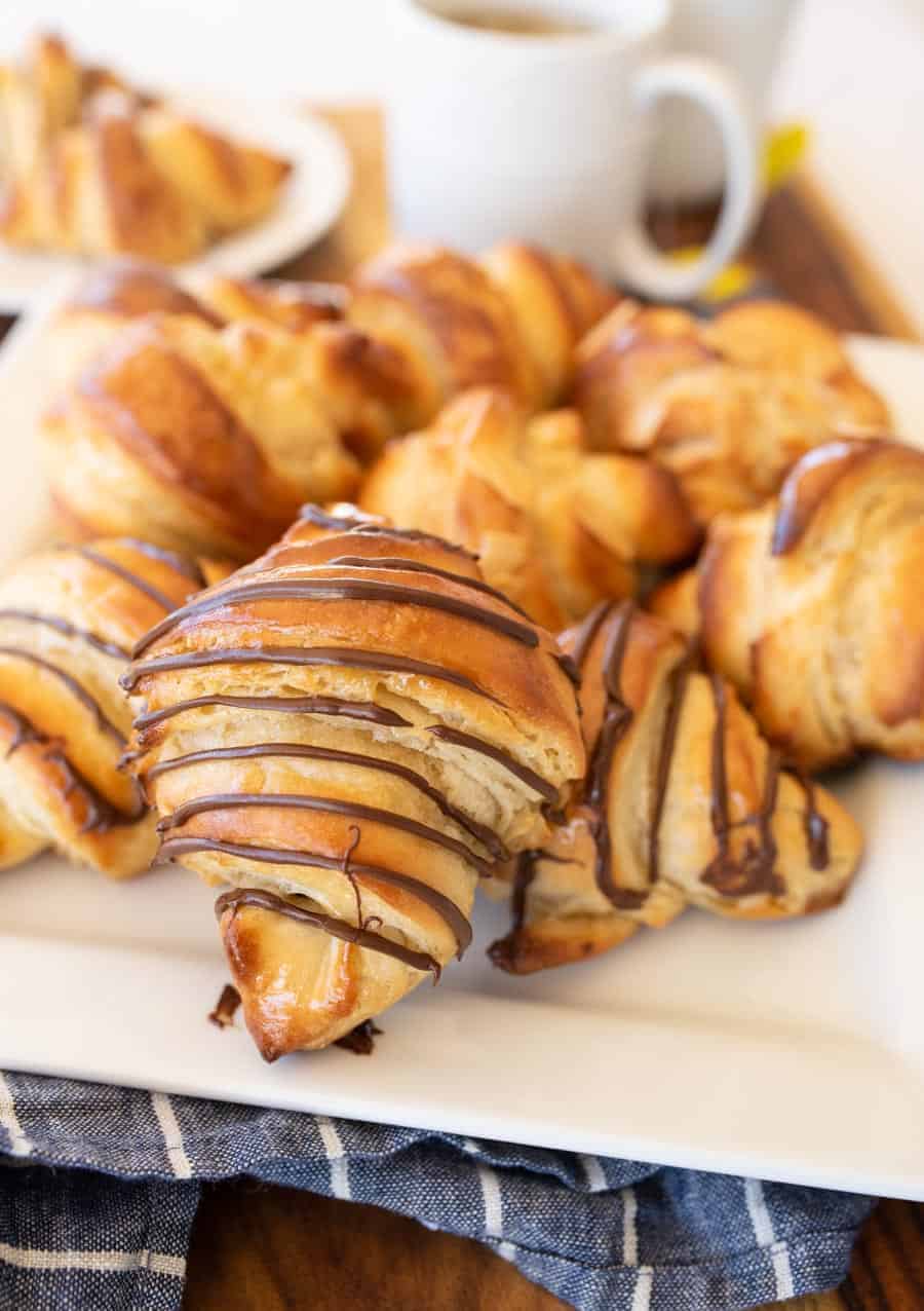 three kinds of croissants on a white plate with tea