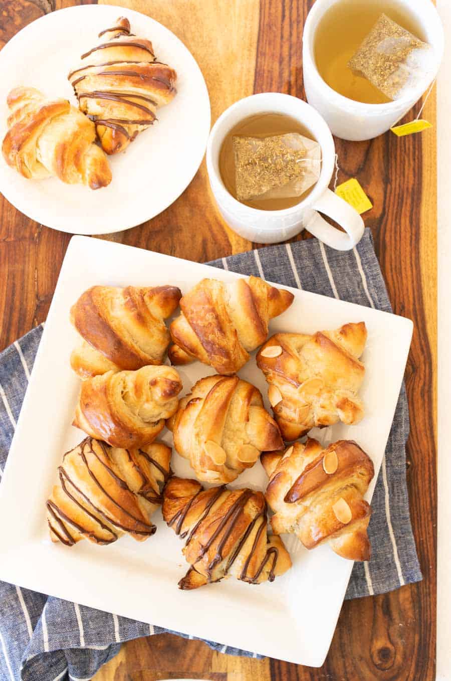 three kinds of croissants on a white plate with tea