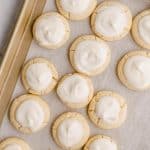 above shot of melt away cookies with white icing on a cooking sheet with parchment paper