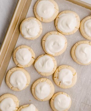 above shot of melt away cookies with white icing on a cooking sheet with parchment paper