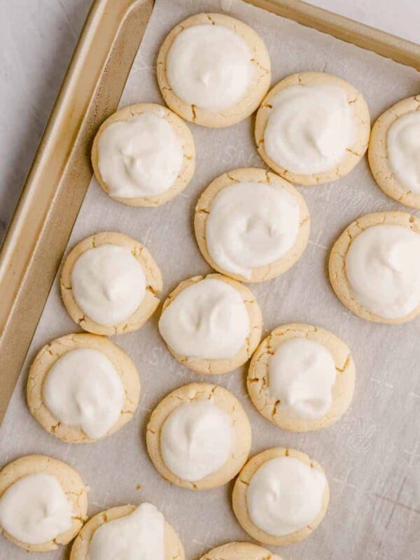 above shot of melt away cookies with white icing on a cooking sheet with parchment paper