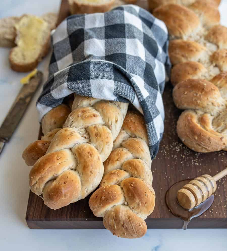 three small loaves of bread whole wheat bread wrapped in a black and white checked towel