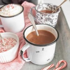 mugs filled with crock pot hot chocolate with a spoon in them