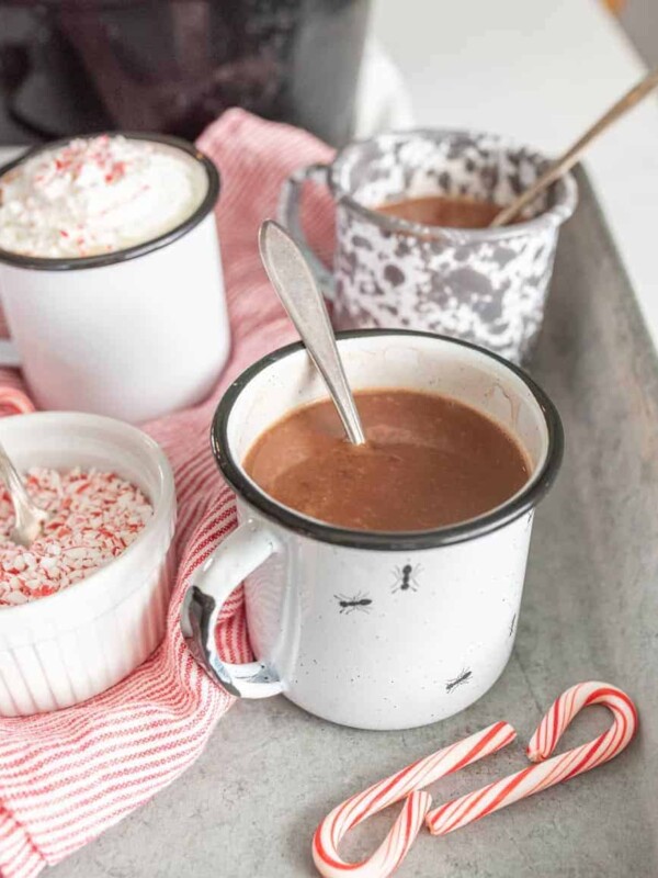 mugs filled with crock pot hot chocolate with a spoon in them