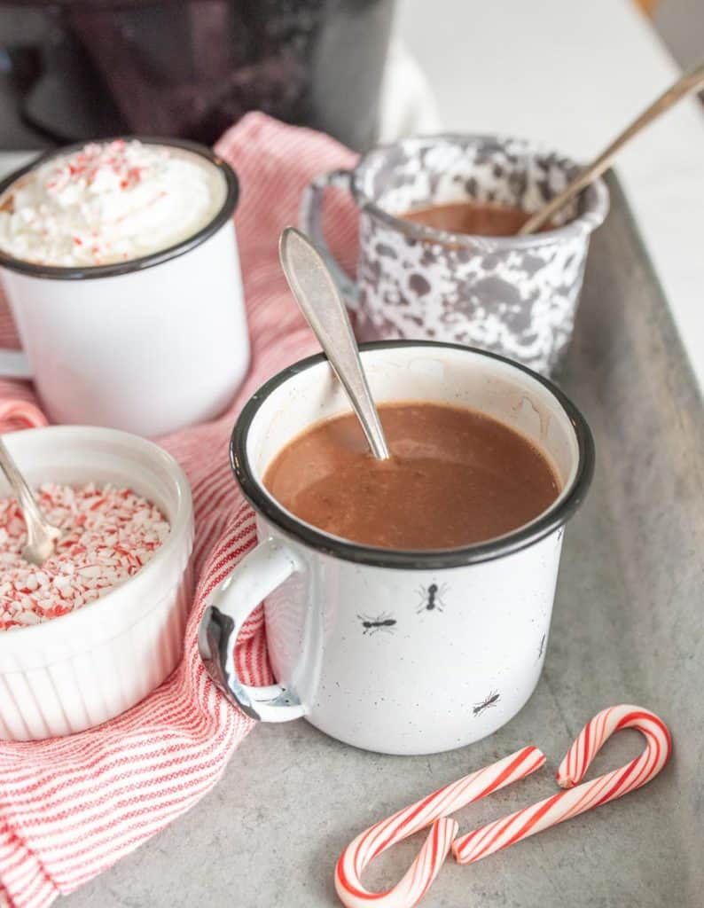 mugs filled with crock pot hot chocolate with a spoon in them