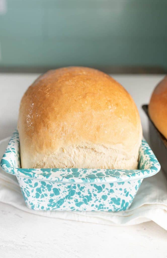 loaf of white sandwich bread in a white and blue speckled loaf pan.