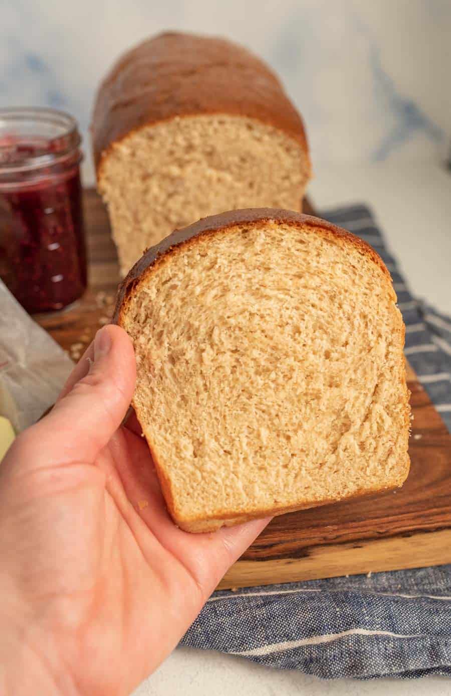 hand holding a slice of whole wheat sandwich bread