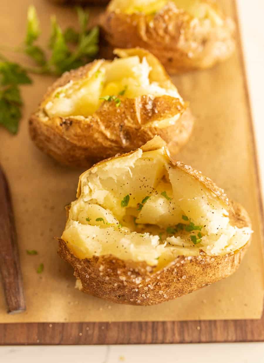 close up view of baked potato with other baked potatoes in the background