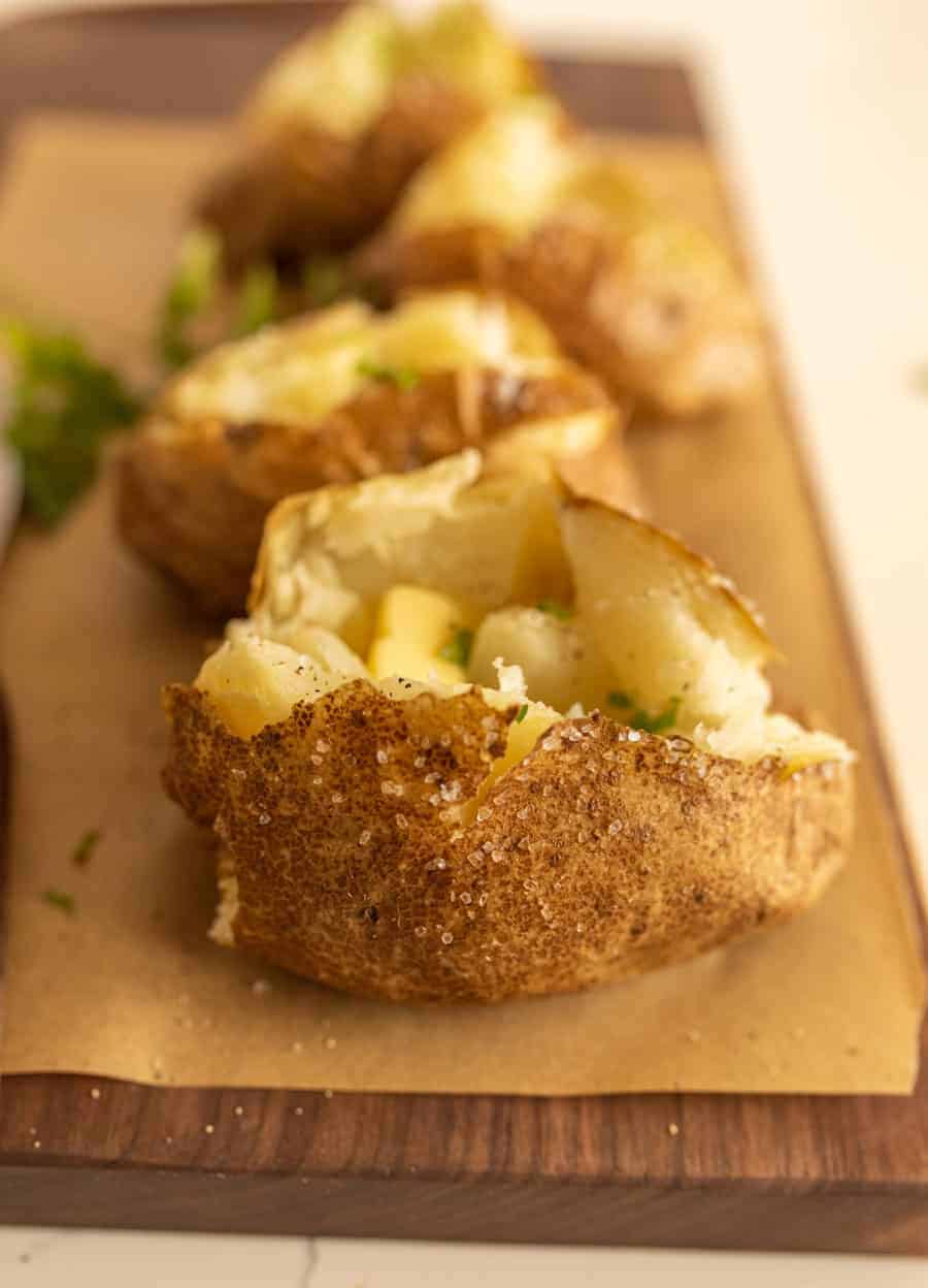 close up view of baked potato with baked potatoes in the background