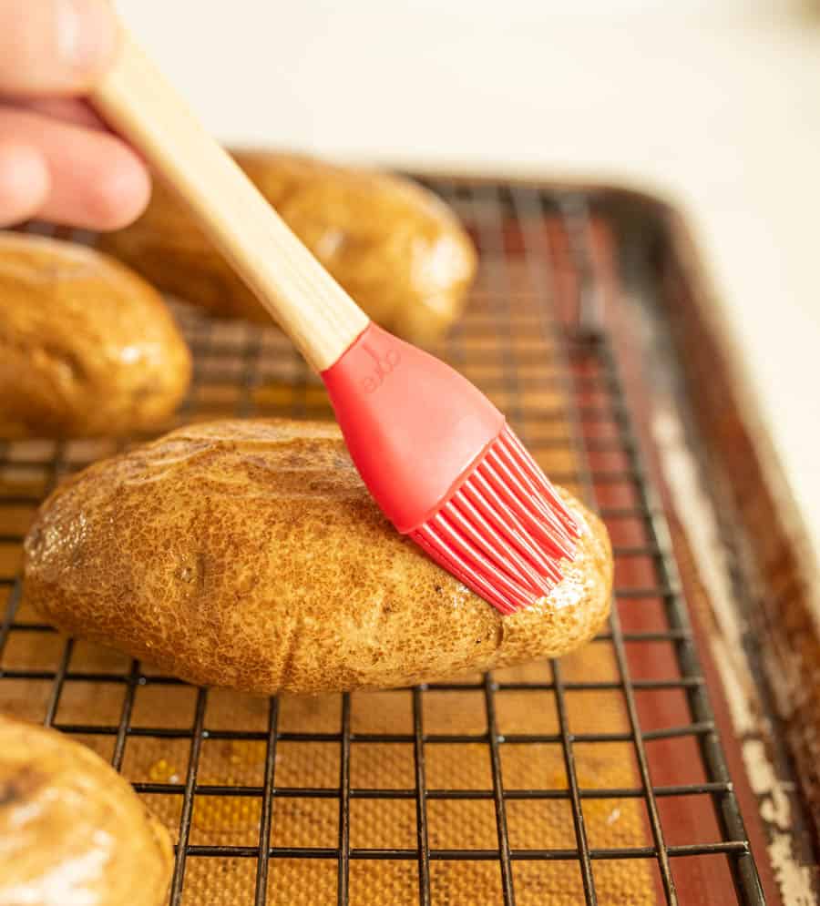 Potato being brushed with oil by pastry brush
