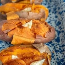 four baked sweet potatoes with butter on them in a baking dish