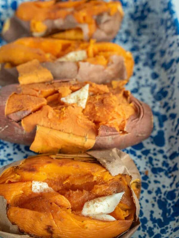 four baked sweet potatoes with butter on them in a baking dish