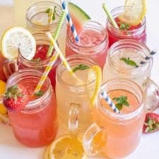Glass mugs filled with different types of lemonade with straws in them