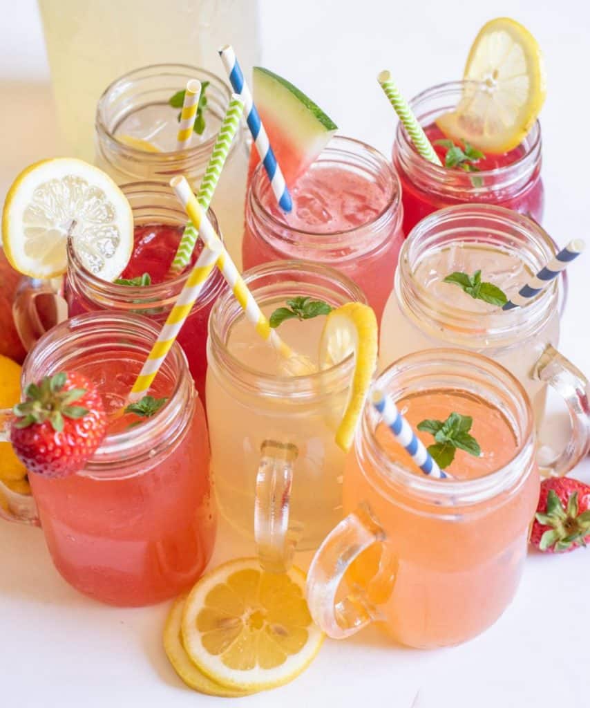 Glass mugs filled with different types of lemonade with straws in them