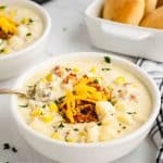 creamy potato soup with an instant pot in the background and garnished with cheddar cheese and greens