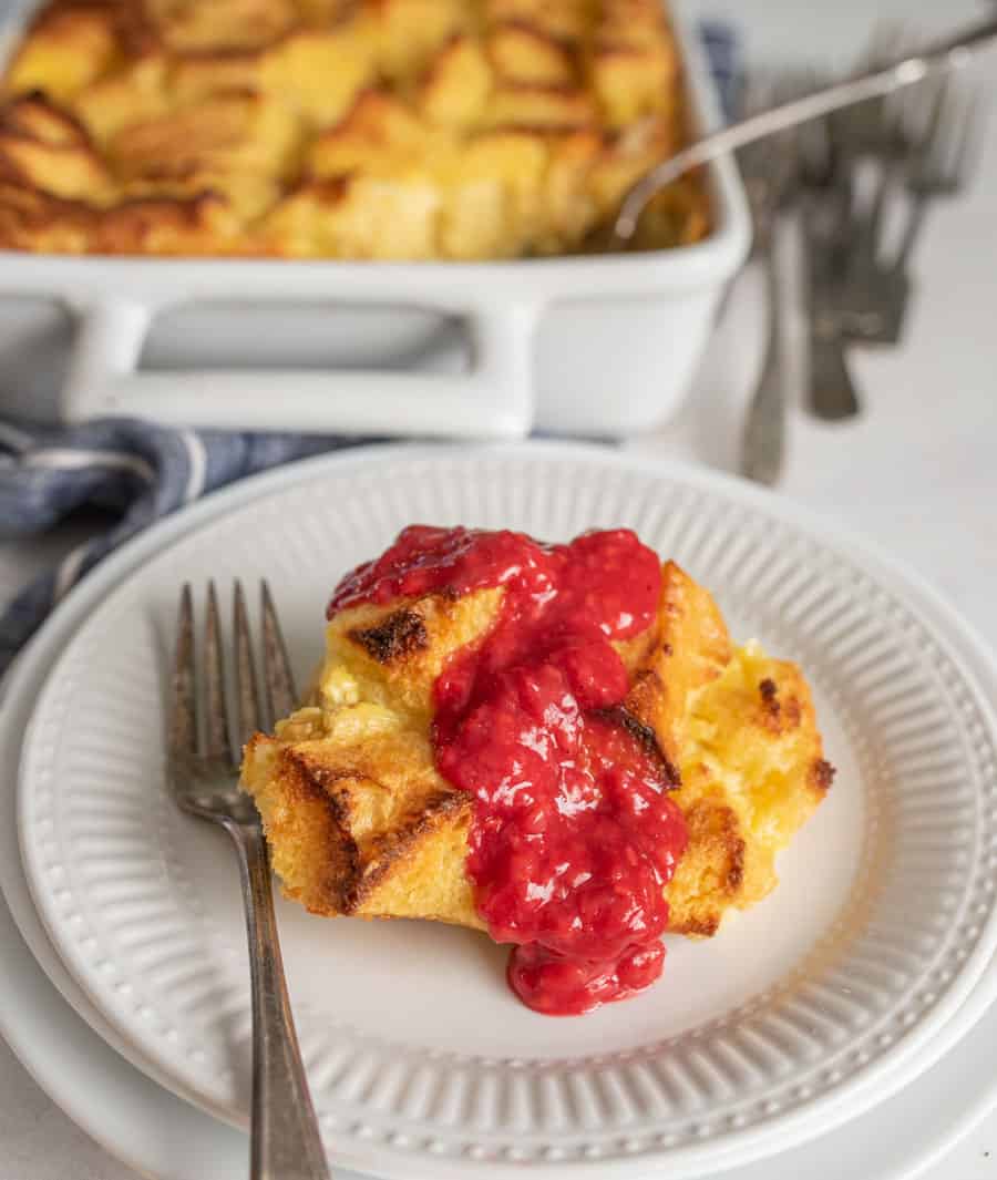 French toast breakfast casserole topped with raspberry sauce on white plate with fork