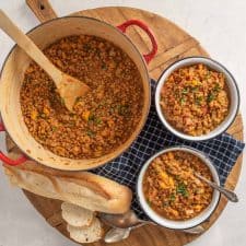 platter with a pot and two bowls of vegetarian lentil soup and French bread on the side