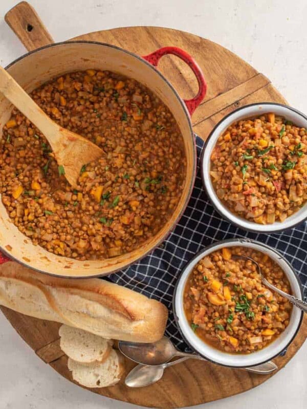 platter with a pot and two bowls of vegetarian lentil soup and French bread on the side