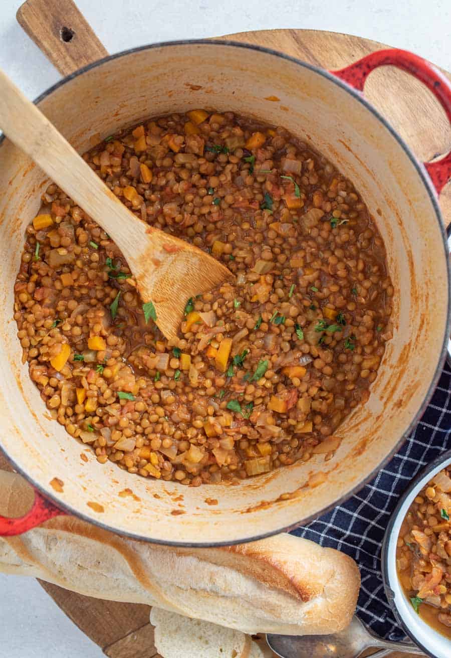 vegetarian lentil soup in large pot with wood spoon in it