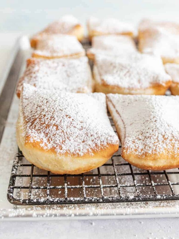 close up of beignets dusted with powdered sugar on a tray