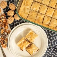 top view of a plate and pan of baklava with walnuts around them