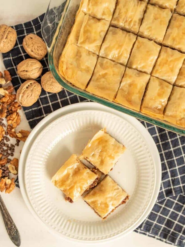 top view of a plate and pan of baklava with walnuts around them