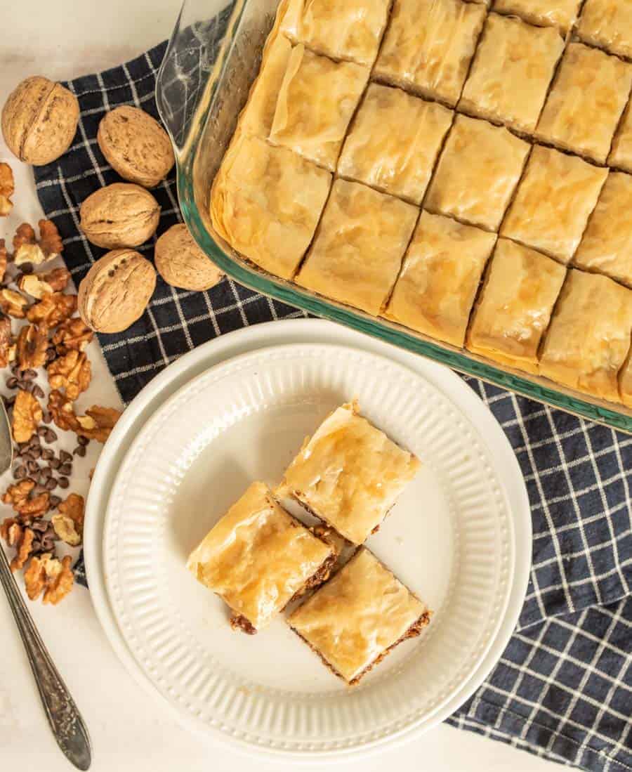 top view of a plate and pan of baklava with walnuts around them