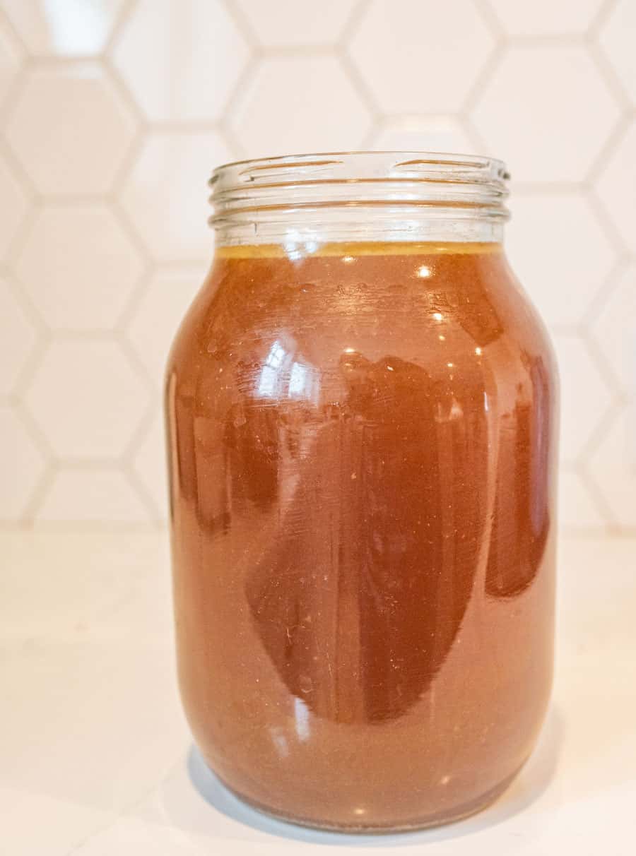 Picture of a glass jar filled with chicken broth.