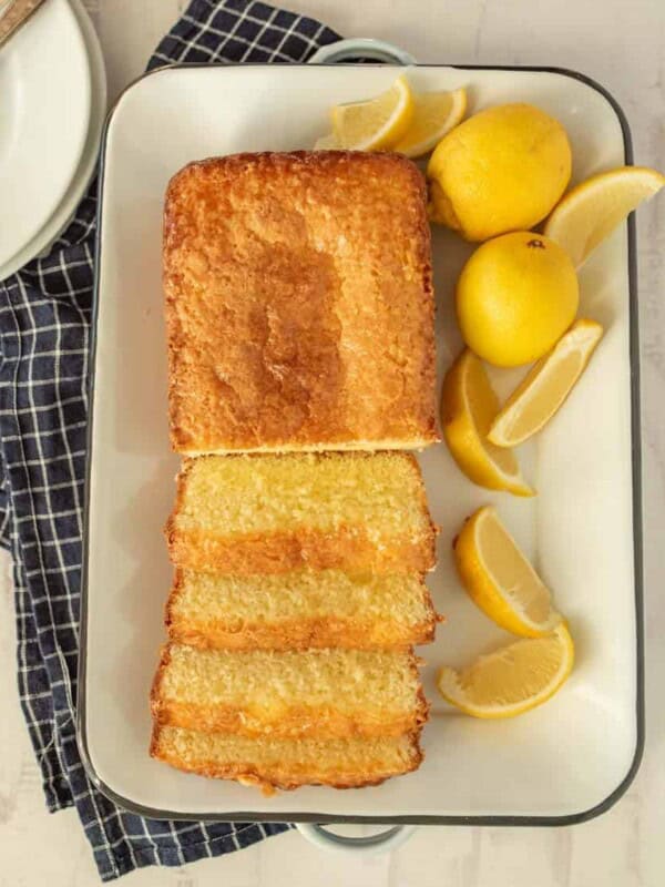 top view of lemon pound cake sliced up on a tray with lemons next to it