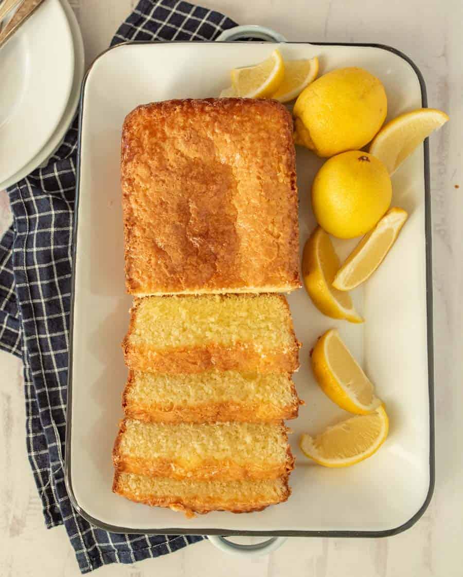 top view of lemon pound cake sliced up on a tray with lemons next to it