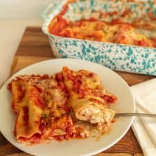 plate of manicotti with a pan of manicotti in the background