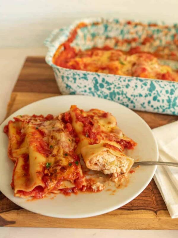 plate of manicotti with a pan of manicotti in the background