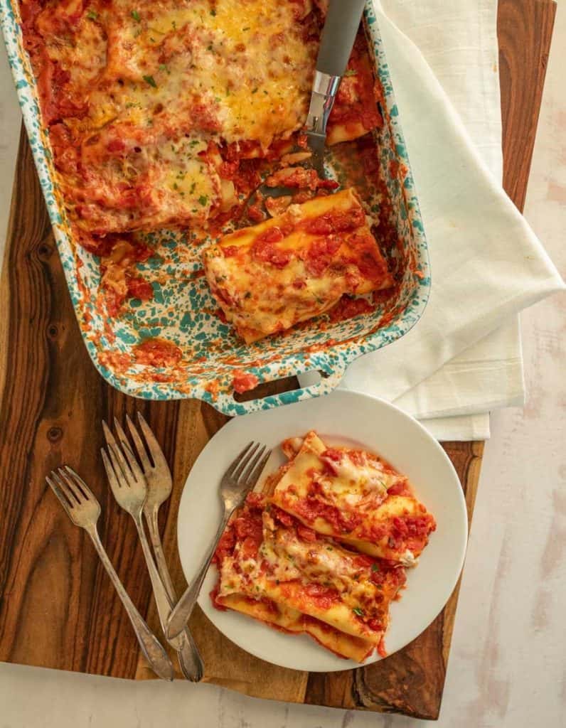 top view of a plate of manicotti and forks next to a pan of manicotti