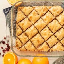 top view of baklava in a pan with oranges and cranberries around the dish